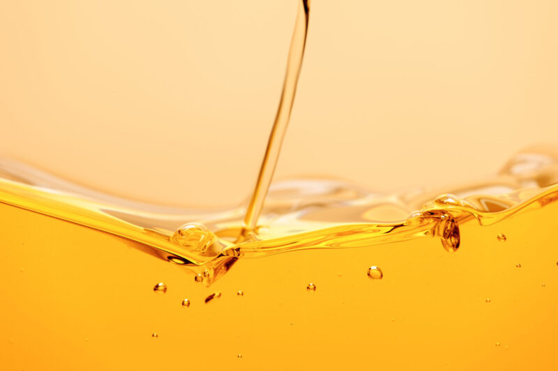 Yellow bright liquid stream with splash and bubbles isolated on yellow