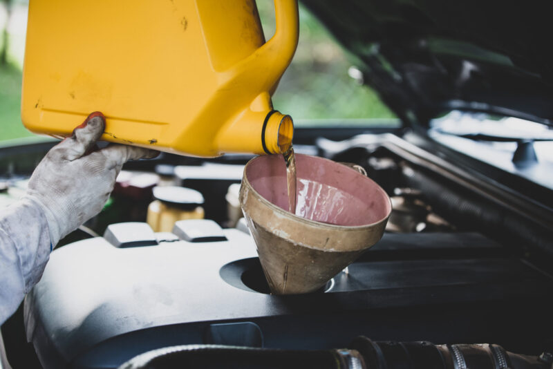 Close up Auto mechanic hand pouring and replacing fresh oil into